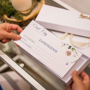Hands holding an elegant gift voucher with delicate typography and floral patterns